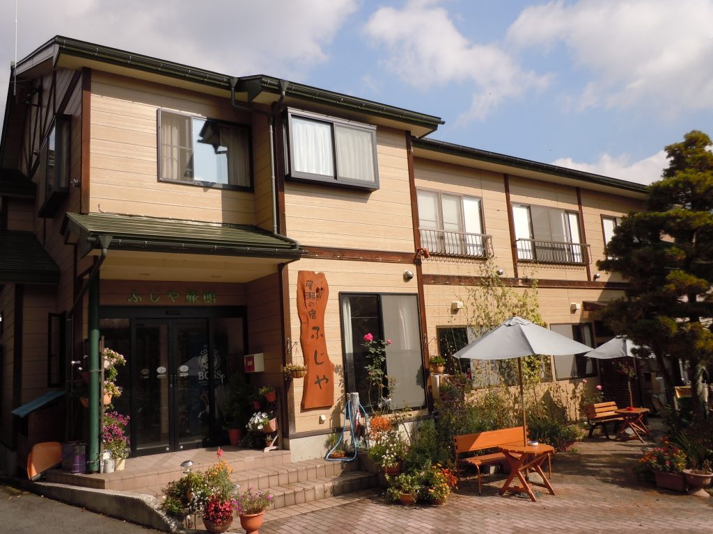 The ryokan facade with plants and outdoor seating.
