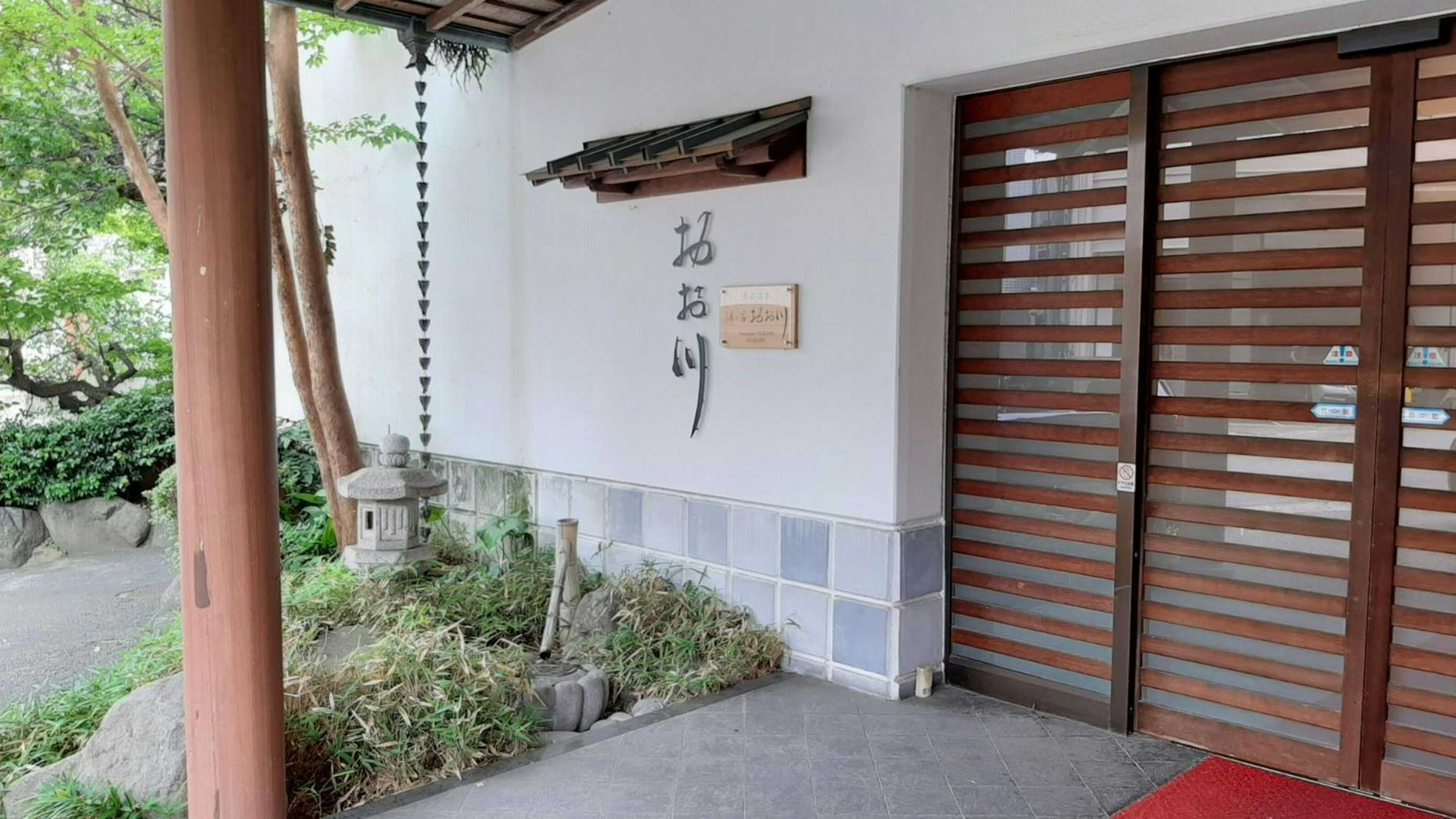 Atami Onsen Yunosuke Ookawa with a sheltered entrance with dark wooden sliding doors.