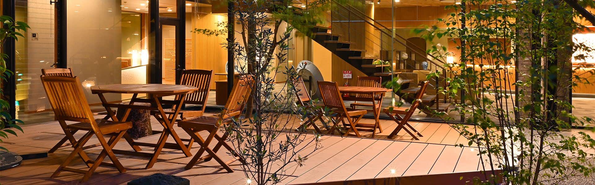 Harazuru Onsen Harazuru no Mai courtyard deck seating surrounded by plants and illuminated windows