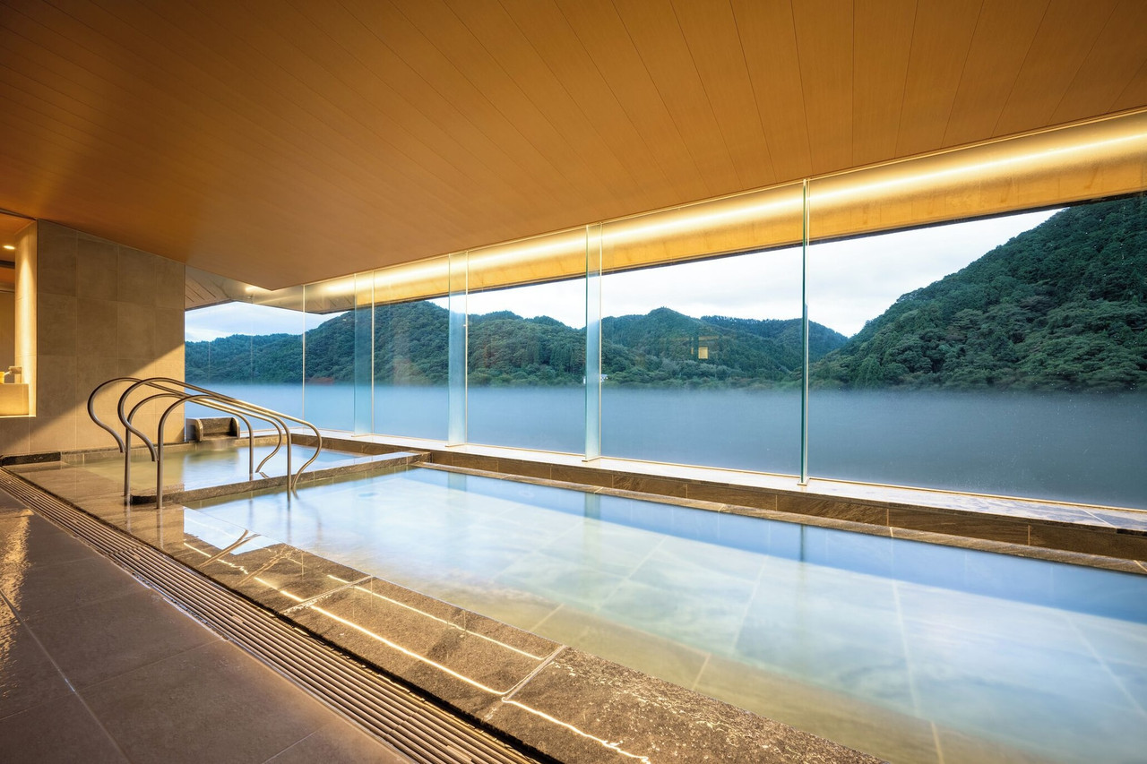 A glass-walled pool overlooks a forested lake.