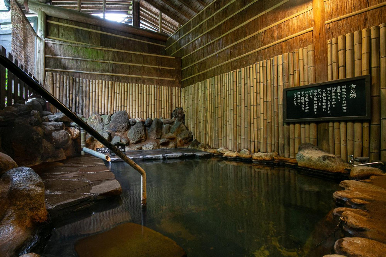 A large bath beneath a timber roof.