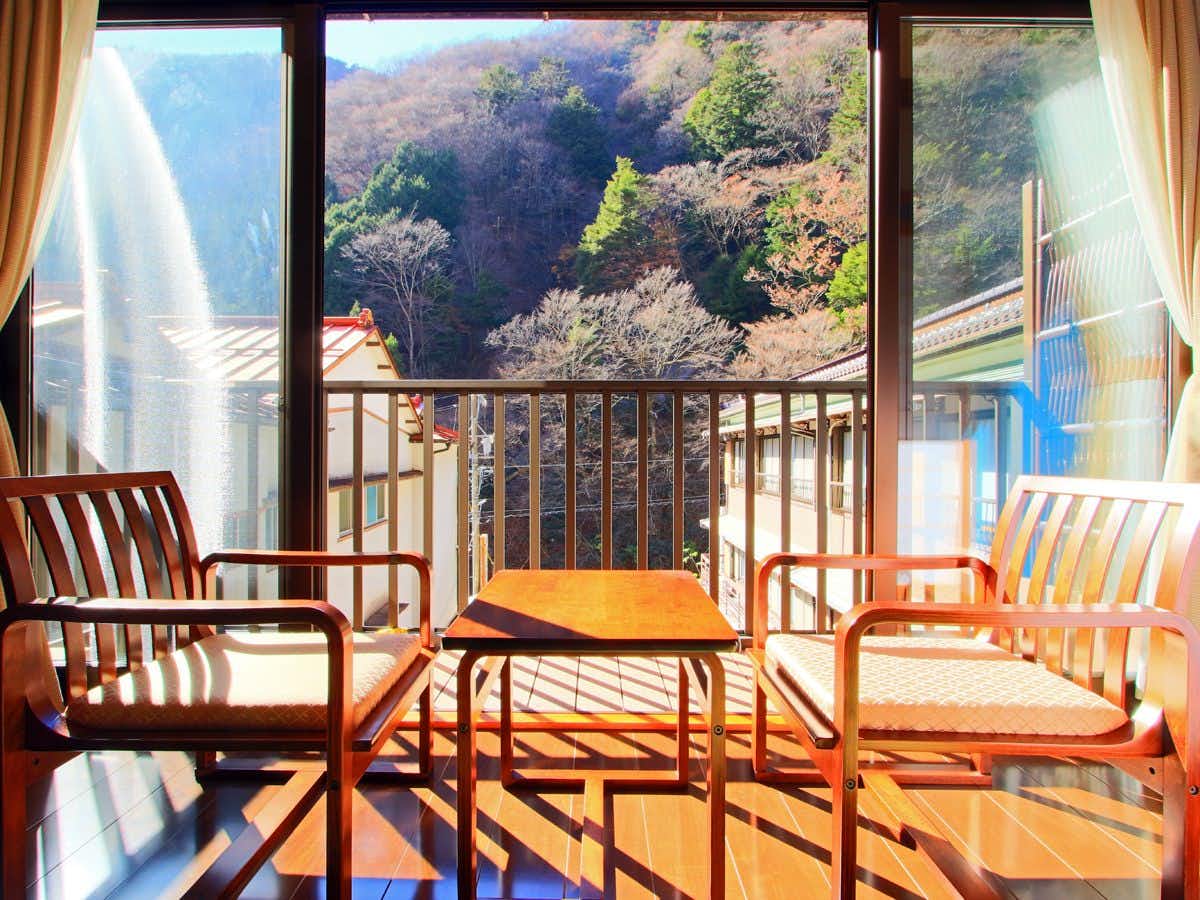 Umegashima Onsen Izumiya Ryokan with a balcony seating area overlooking the forested valley.