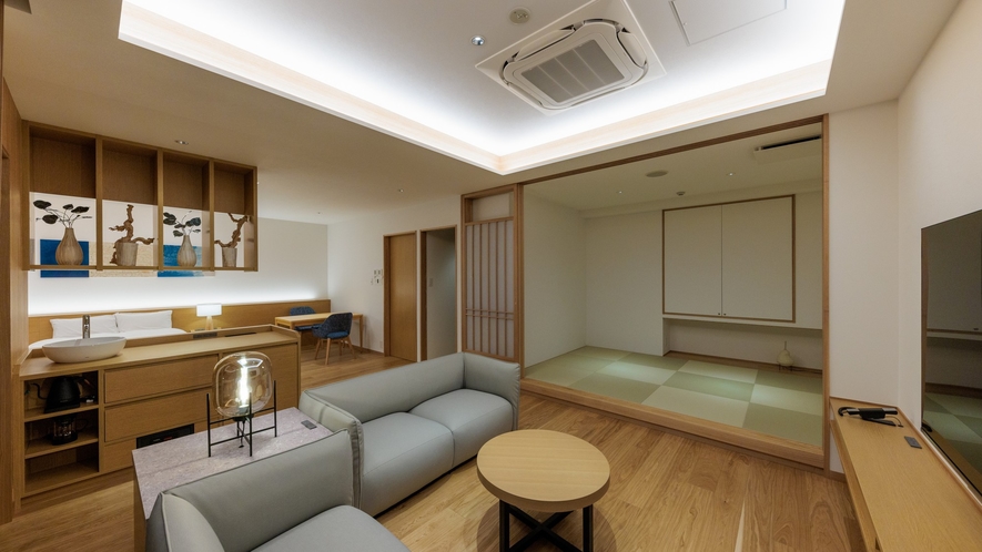 A modern sitting area with a sofa beside a raised tatami room.