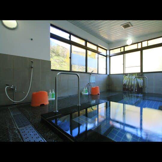 Yugawa Onsen Izumiya Ryokan <Fukushima Prefecture> with a bright communal bath with blue tiles and tall windows.