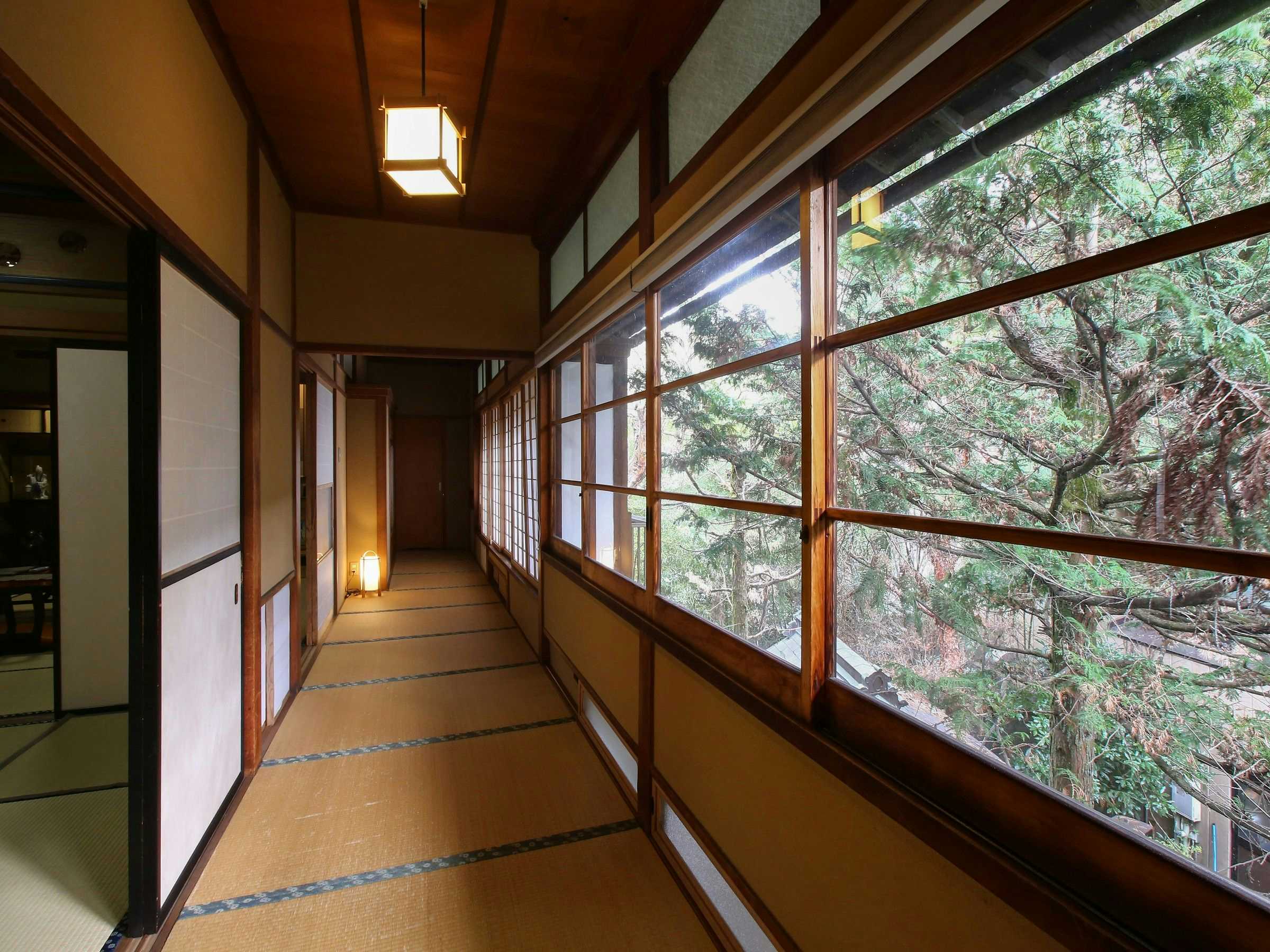 Kisoji no Yado Iwaya with a long tatami corridor overlooking leafy trees through broad windows.