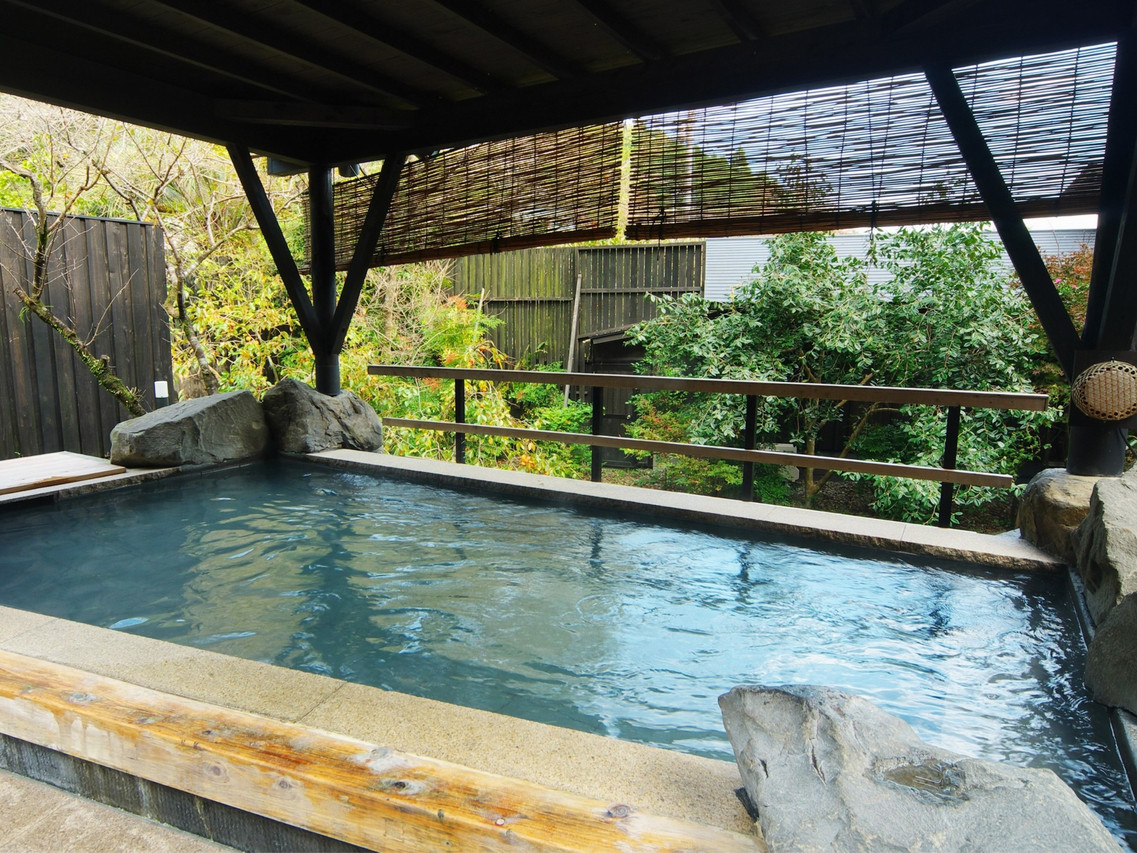 Covered outdoor bath with a rock surround.