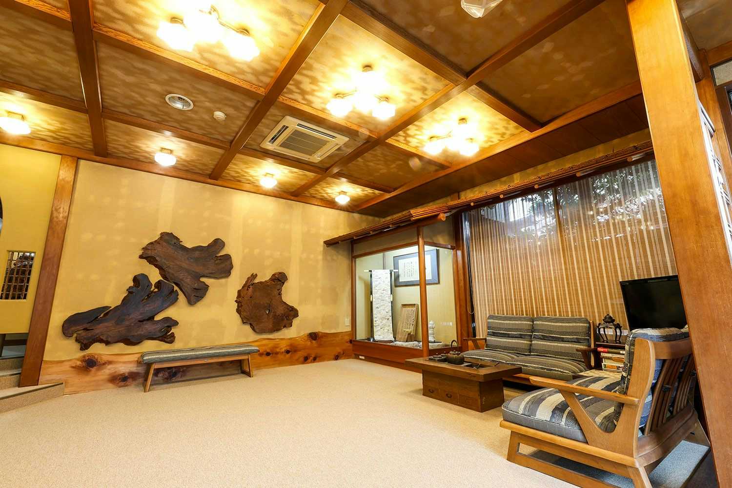 Kinosaki Onsen Yanagiso with this scene, where a timber-ceilinged lounge uses carved wood panels and low seating around the walls.
