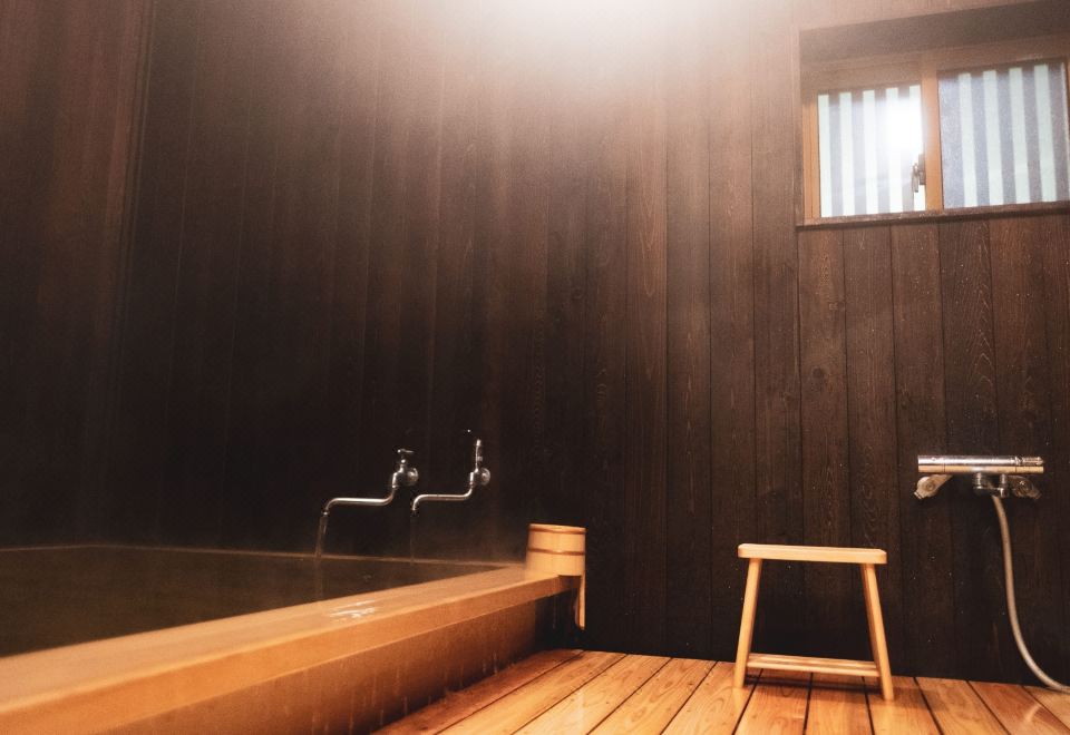A compact wooden bath is finished with dark timber walls.