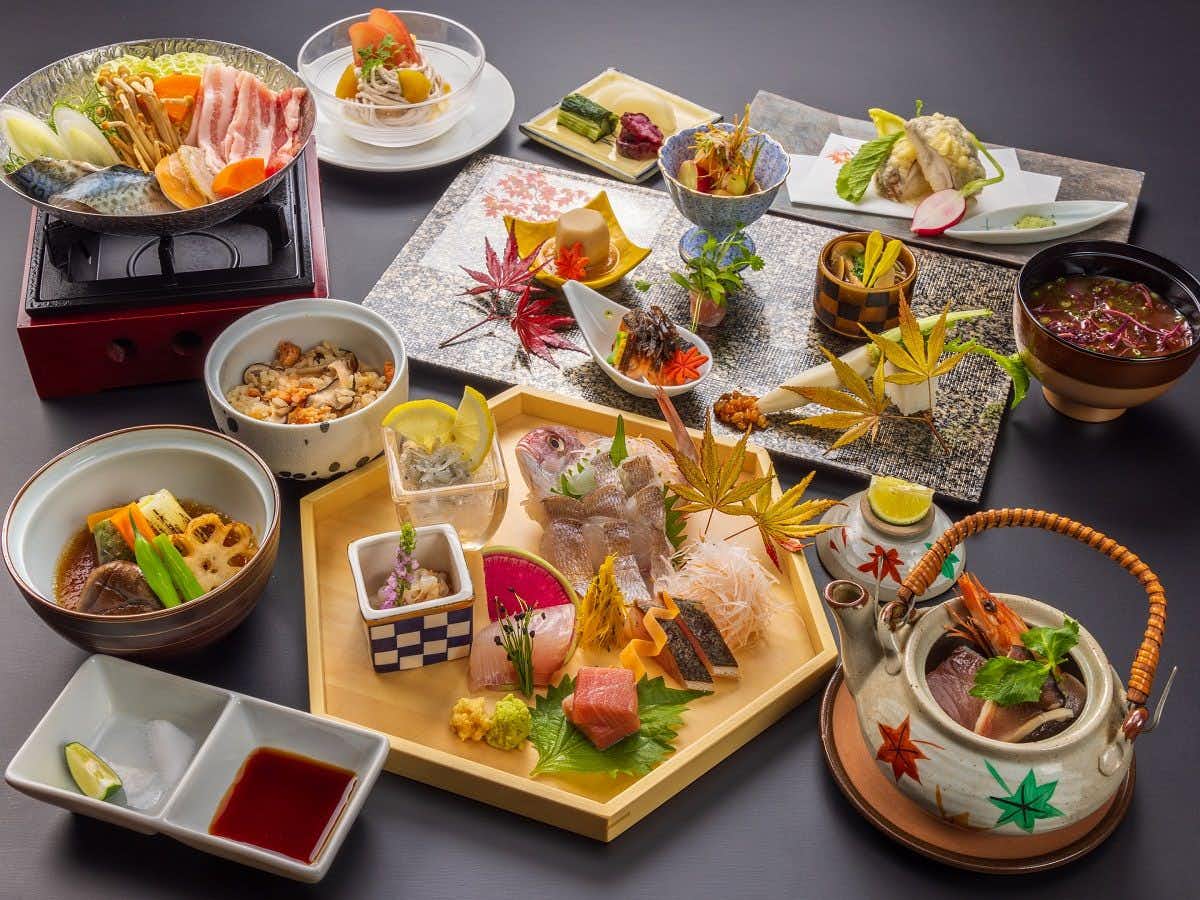 Atami Onsen Yamaki Ryokan with a colorful Japanese dinner arranged across individual dishes.