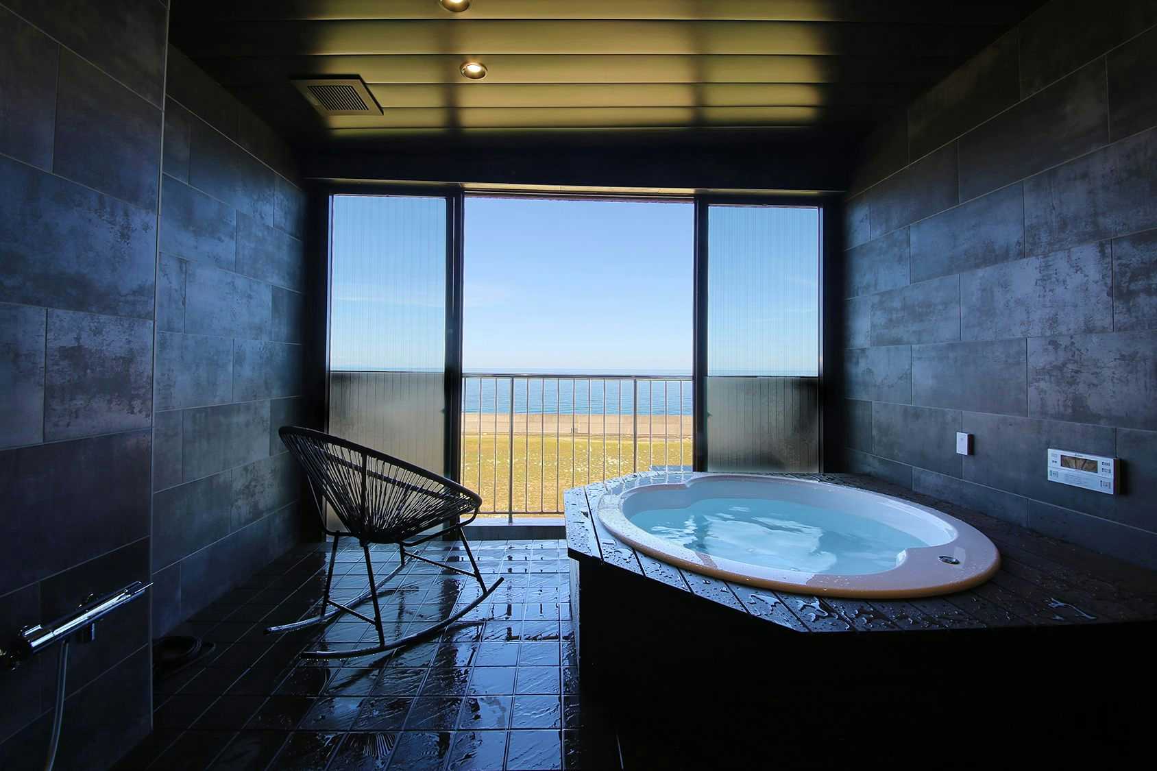 Bettei Yadokari with a private round bath facing the ocean through broad windows.