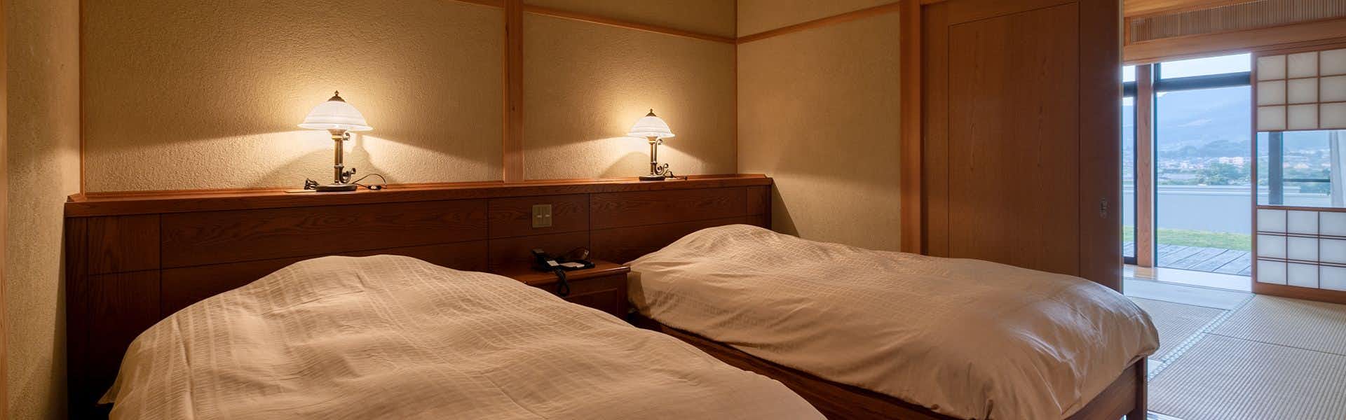 Yufuin Onsen Higashi Shouan with a warm twin bedroom with pale bedding and timber headboard.