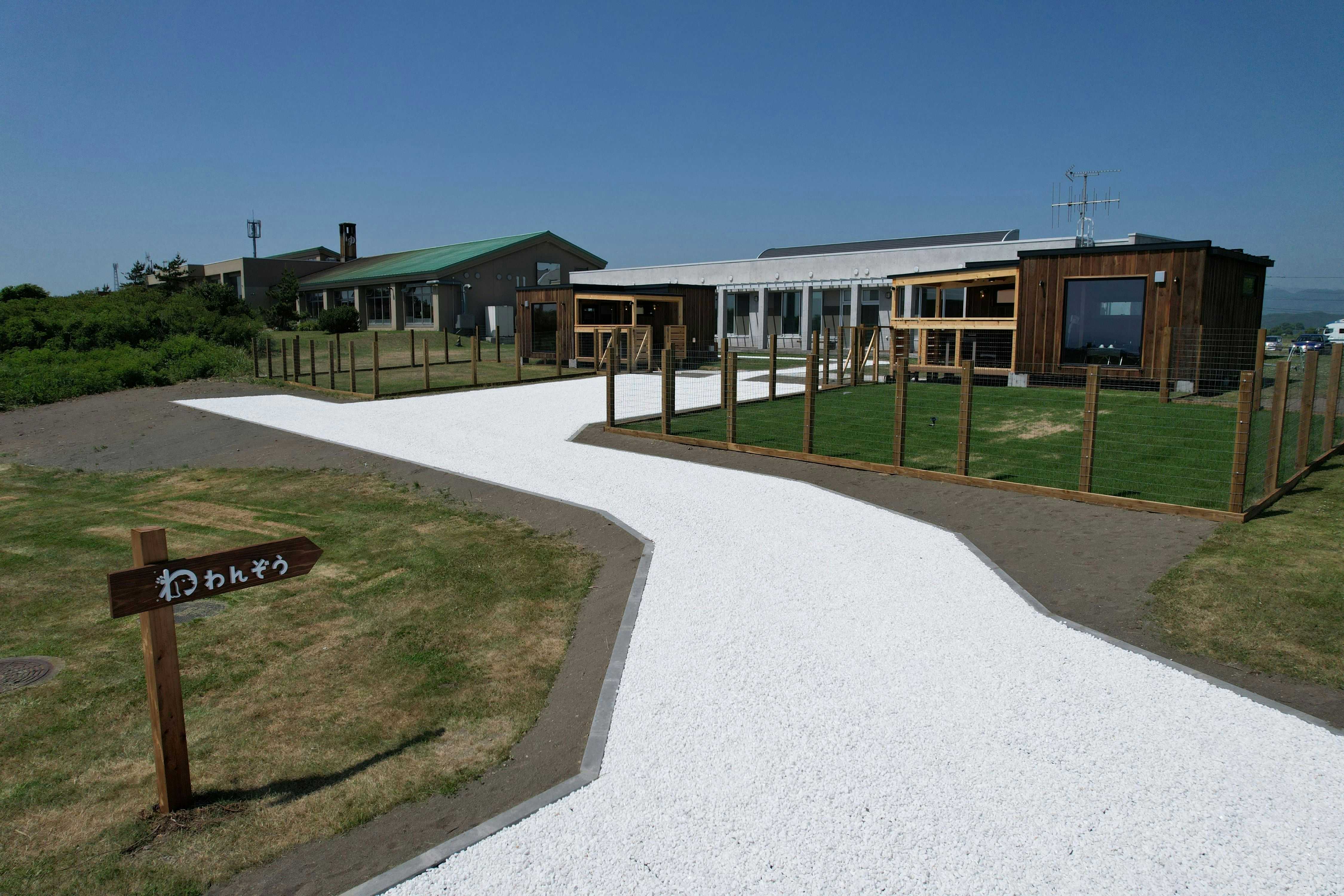 Mitsuishi Kombu Onsen Kurazo with low modern buildings beyond a broad white garden path.