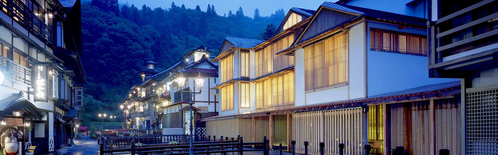 Ryokan Fujiya with the illuminated Ginzan Onsen street at blue hour.