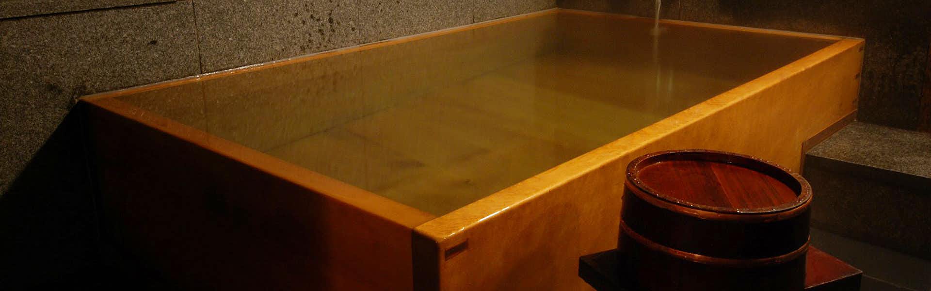 Kurashiki Bikan District Yoshi Ryokan with a private rectangular timber bath beside dark stone walls.