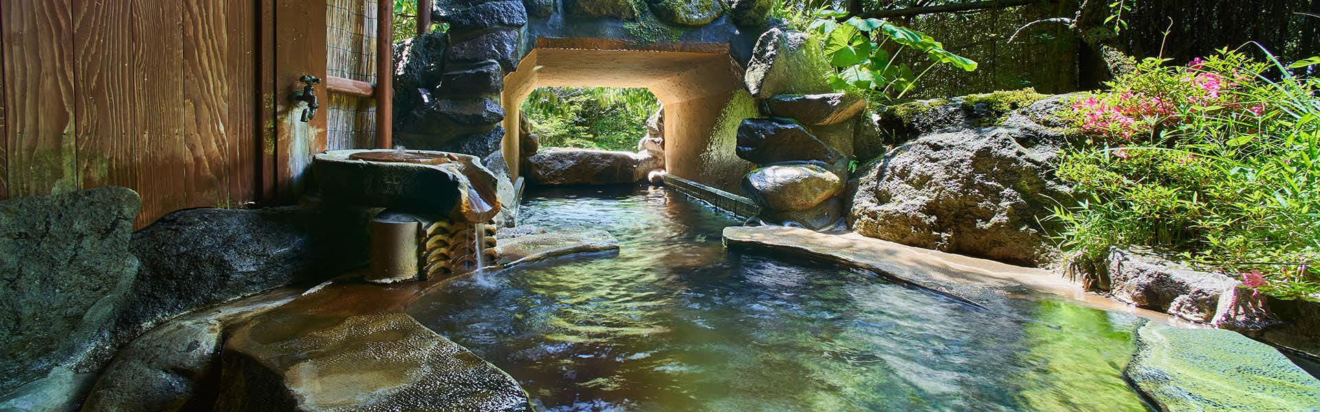 Hanare Yado Yamazaki with an open-air stone bath surrounded by rocks and garden greenery.