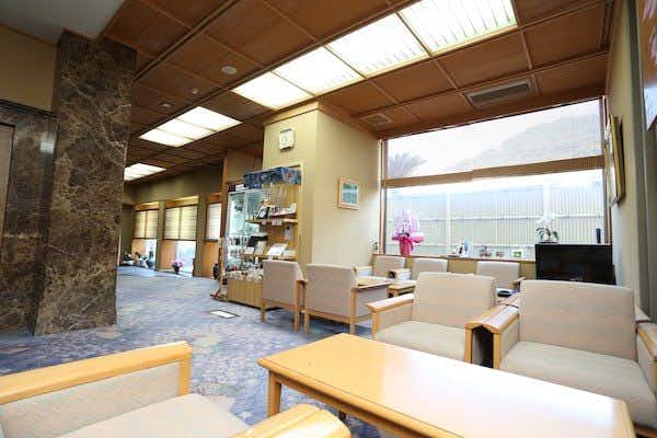 Hotel Kappo Ishimaru: The Inn of Echizen Crab and Natural Abalone Bright lobby with pale lounge chairs, low tables, stone columns, display shelves, and ceiling skylights