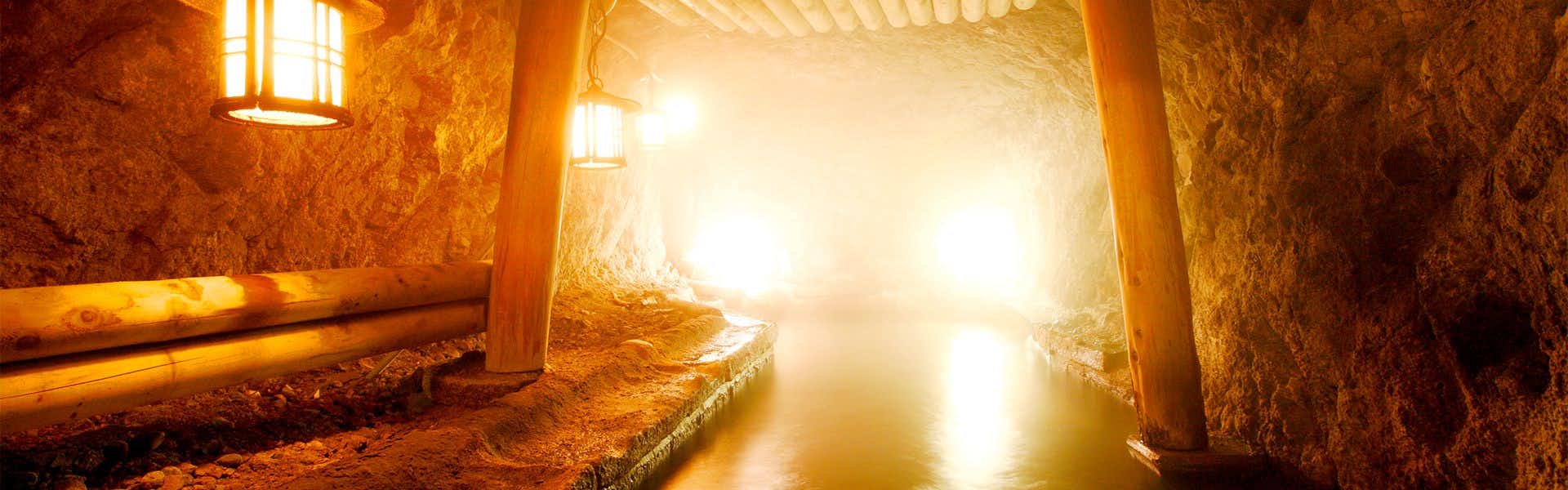 Bokusuisou Toikan Bath facility at night with water, stepping stones, covered shelter, and architectural lighting elements.