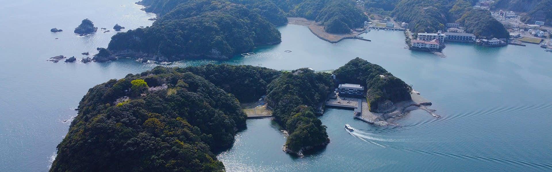 Aoki Shima no Yado Kumano Bettei Nakanoshima Aerial view of multiple forested islands in bright turquoise water with moored vessels