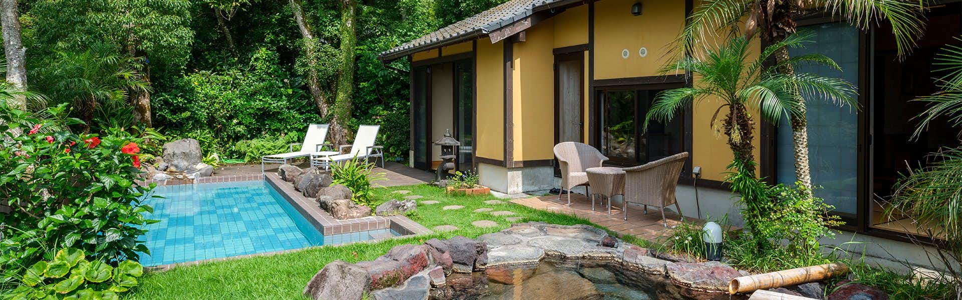 Hot Spring Water Pool & Private Open-Air Bath  YURIAN with a secluded rock bath and blue pool among tropical greenery.