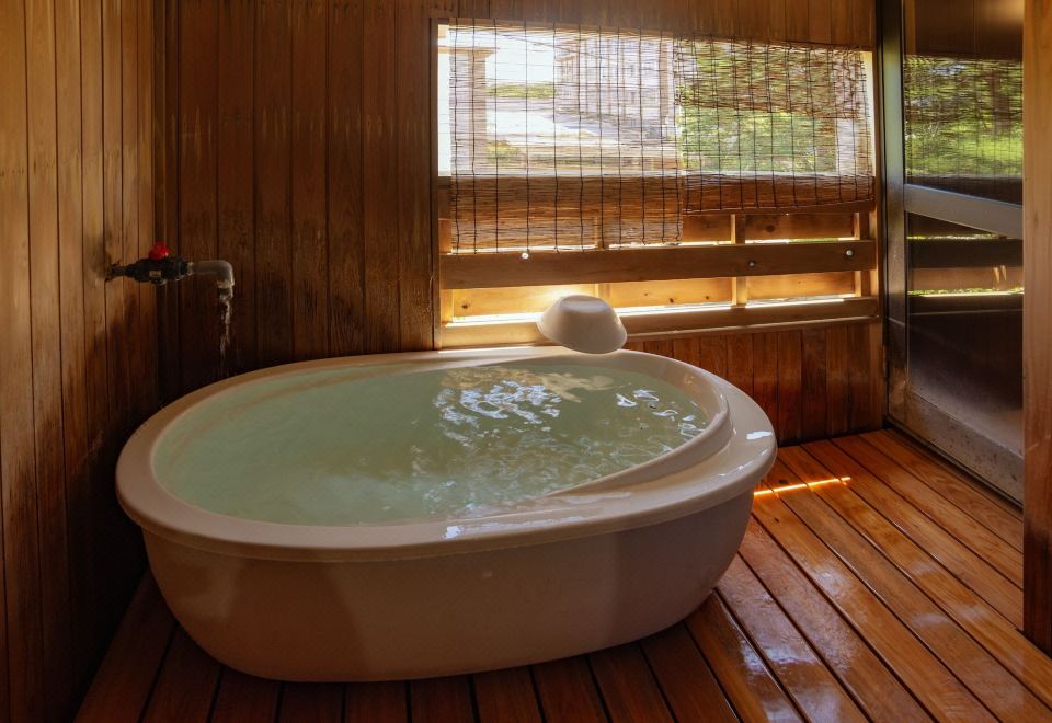 A pale oval bathtub in a wood-paneled bathing room.