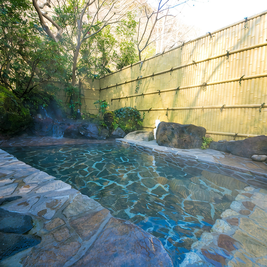 Outdoor bath beside a wooded slope.