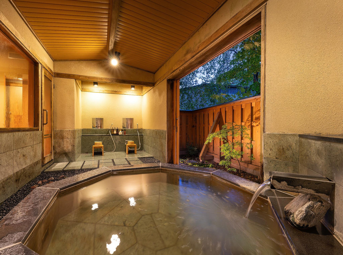 A bedroom looks onto a private indoor bathing area.