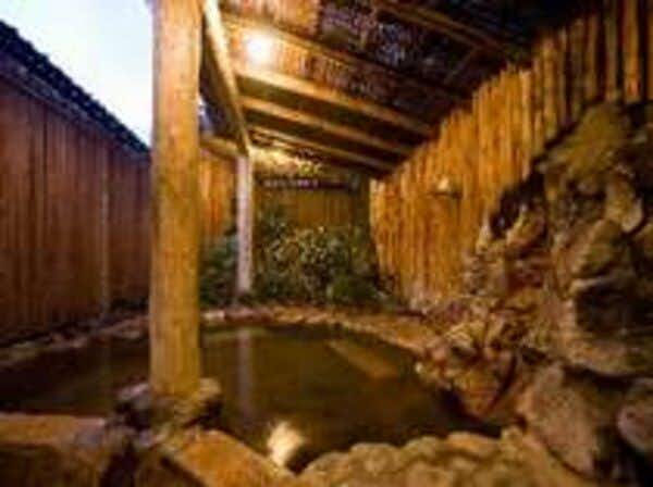 Ryokan Izumoya with this scene, where its roofed stone bath is enclosed by timber posts and a tall bamboo screen.