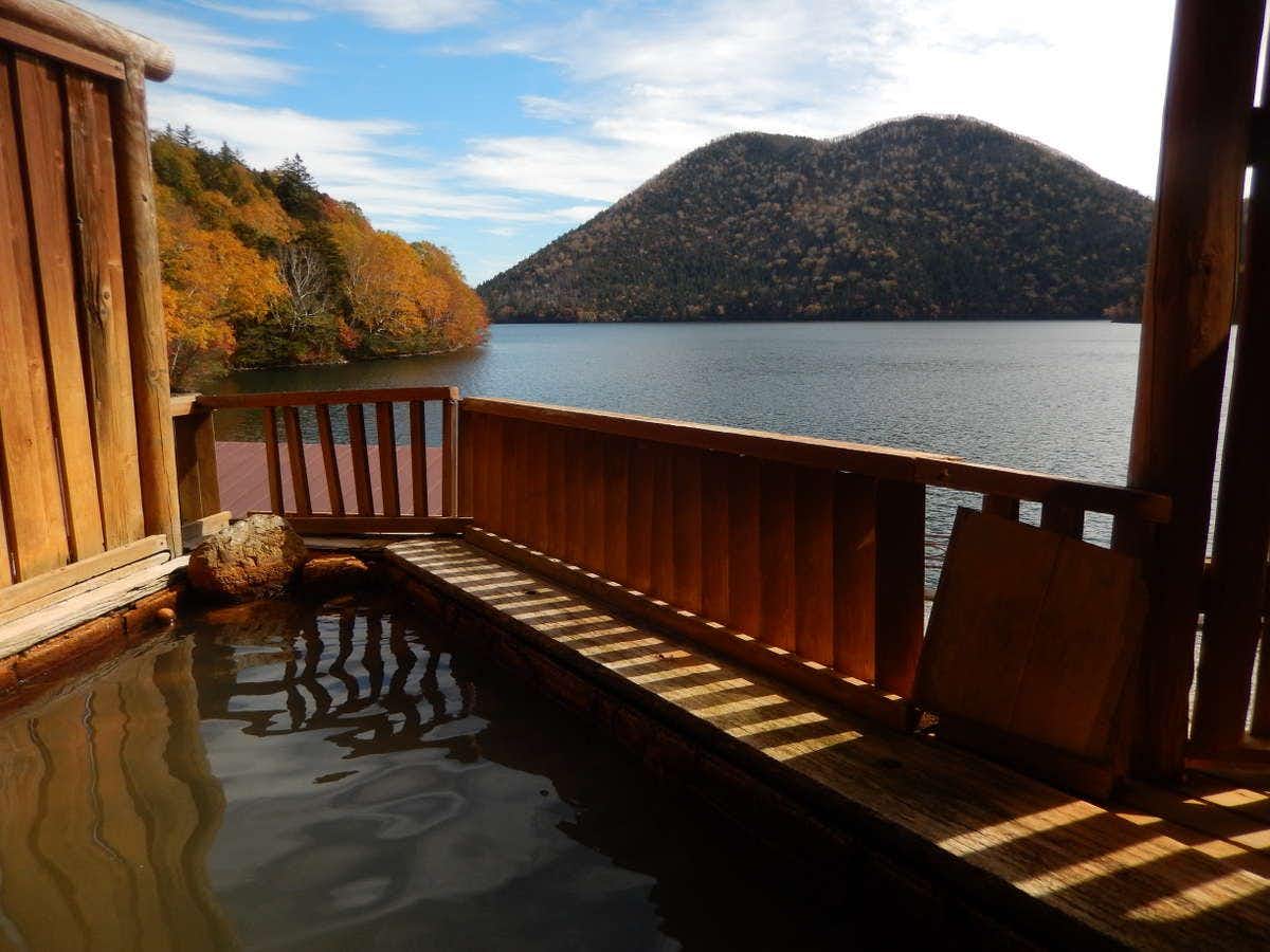 Shikaribetsu Kohan Onsen Hotel Fusui with an outdoor mineral bath overlooking calm lake water.