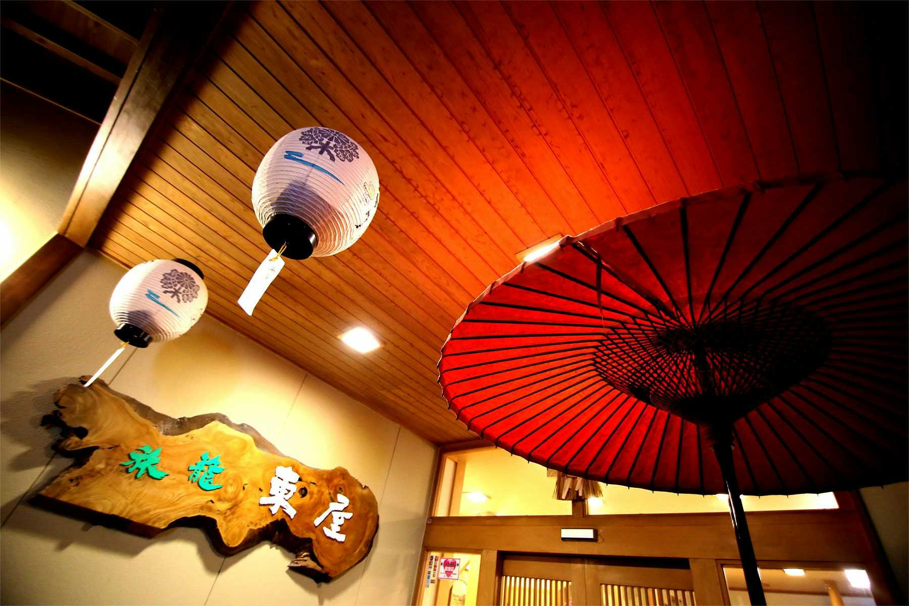 Hatago Azumaya with a red umbrella and paper lanterns decorating the timber entrance.